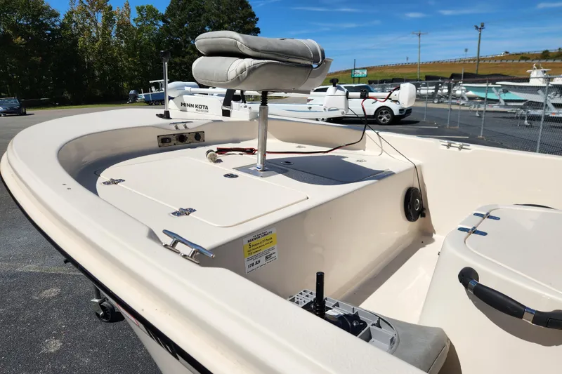 Slide: The Image of 2025 Carolina Skiff 178 JLS boat with Minn Kota motor, parked outdoors under clear skies. - 7