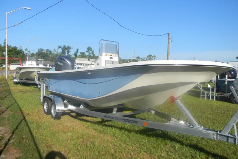 The Image of 2026 Carolina Skiff 21 LS boat on trailer, parked on grass under clear blue sky. - 1