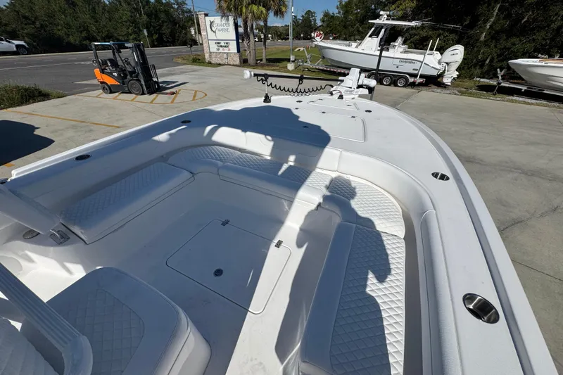 Slide: The Image of 2026 Caymas 281 HB boat interior with white seating and deck, parked outdoors. - 21