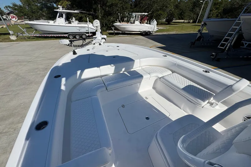 Slide: The Image of 2026 Caymas 281 HB boat interior with white seating and deck, parked outdoors. - 23