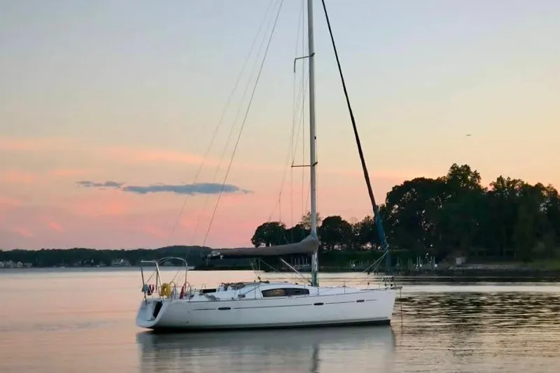 The Image of 2010 Beneteau Oceanis 40 sailboat anchored at sunset on calm water. - 0