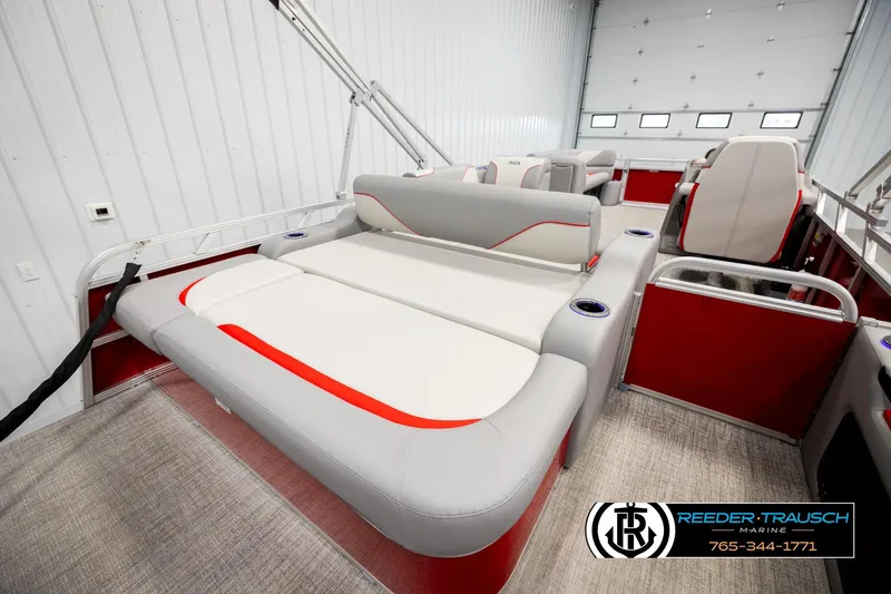 Slide: The Image of 2026 Avalon VEN85 VRB pontoon boat interior with red and gray seating, showcased in a showroom. - 26