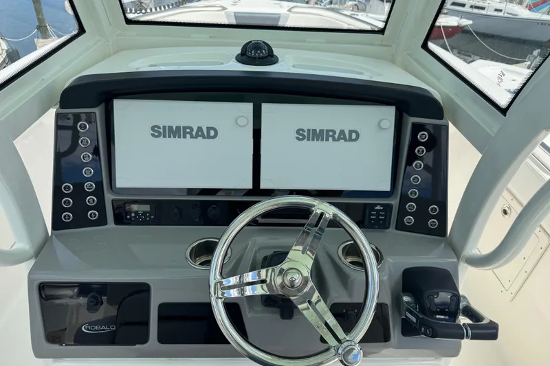 Slide: The Image of 2021 Robalo R272 Center Console helm with dual Simrad displays and steering wheel. - 13