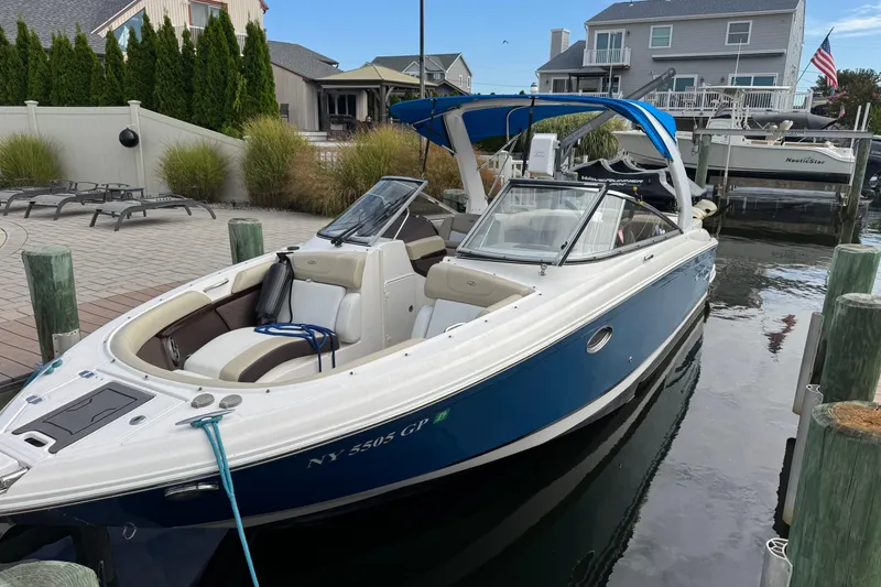 Slide: The Image of 2015 Regal 2700 Bowrider boat docked in a marina, featuring blue and white design. - 2