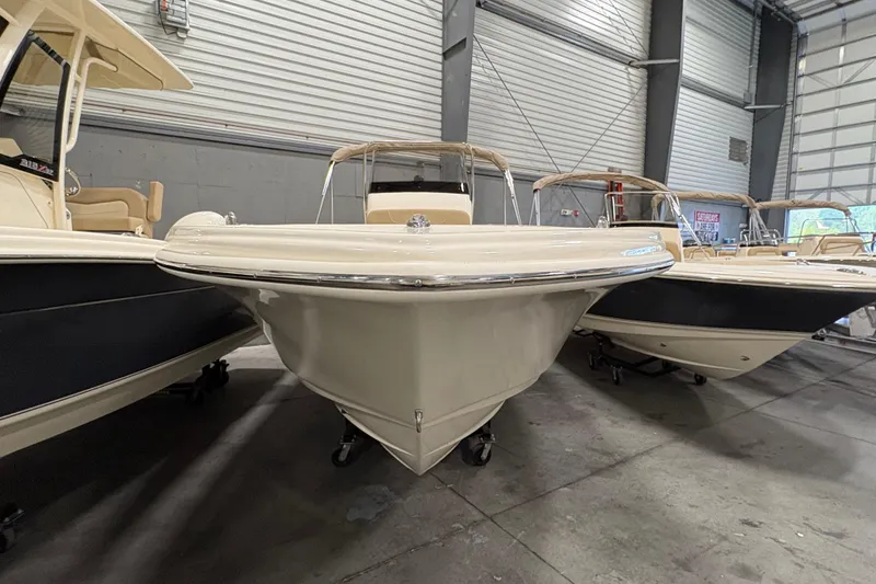 Slide: The Image of 2025 Scout 215 XSF boat in showroom, front view, beige color, indoor display. - 2