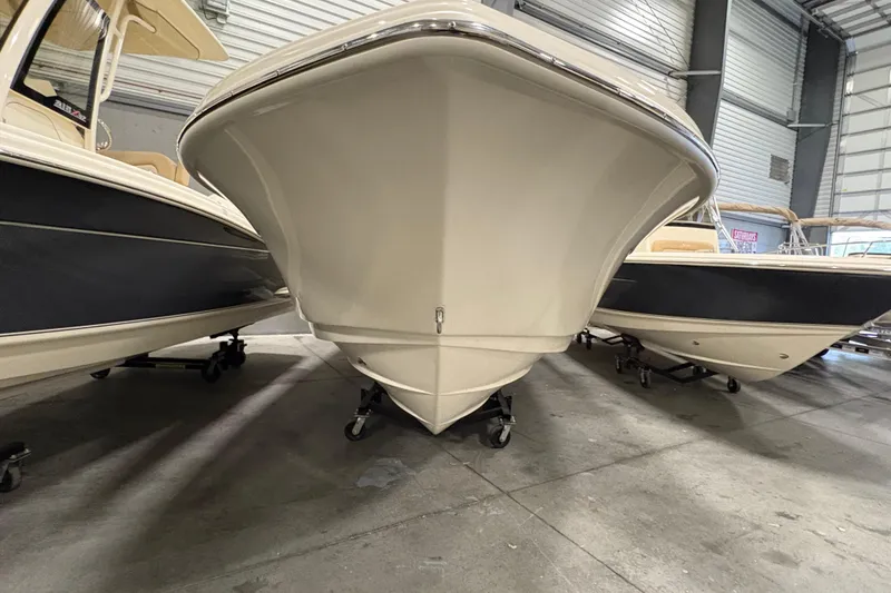 Slide: The Image of 2025 Scout 215 XSF boat in showroom, front view, surrounded by other boats. - 3
