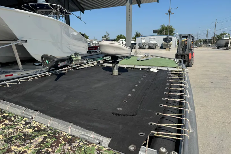 Slide: The Image of 2013 Hanko 19 SC boat with black tarp, parked near other boats and forklift. - 12