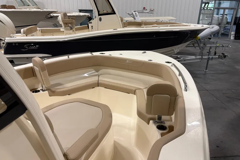 Slide: The Image of 2025 Scout 215 XSF boat interior with beige seating in showroom. - 11