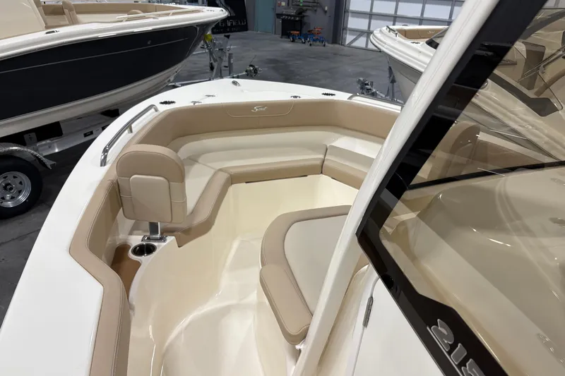 Slide: The Image of 2025 Scout 215 XSF boat interior with beige seating and cup holder in showroom. - 12