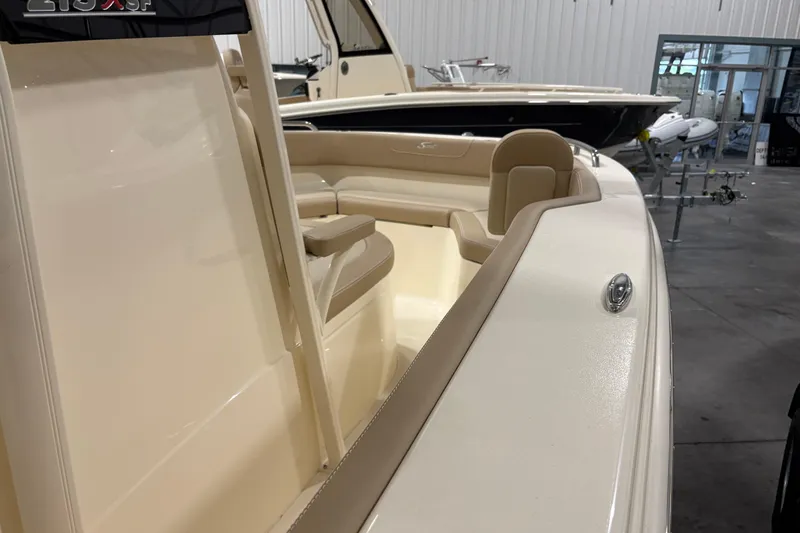 Slide: The Image of 2025 Scout 215 XSF boat interior with beige seating in a showroom. - 9