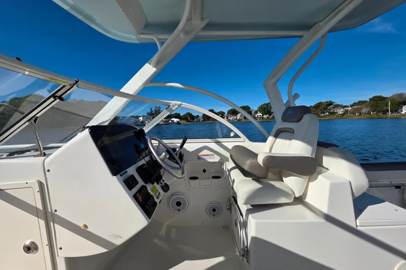 Slide: The Image of 2022 World Cat 255 DC boat cockpit with steering wheel and seating, on a sunny day. - 15