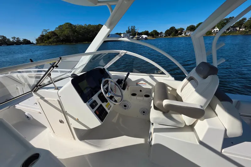 Slide: The Image of 2022 World Cat 255 DC boat cockpit with steering wheel and comfortable seating on a sunny day. - 16