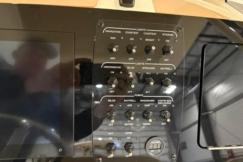 Slide: The Image of Control panel of 2025 Scout 240 XSF boat with various switches and voltage display. - 13