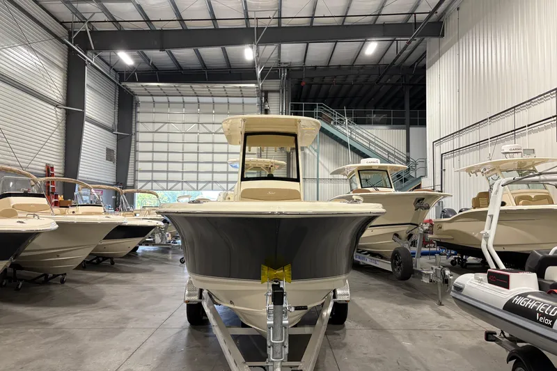 Slide: The Image of 2025 Scout 240 XSF boat in showroom, surrounded by other boats, showcasing sleek design. - 5