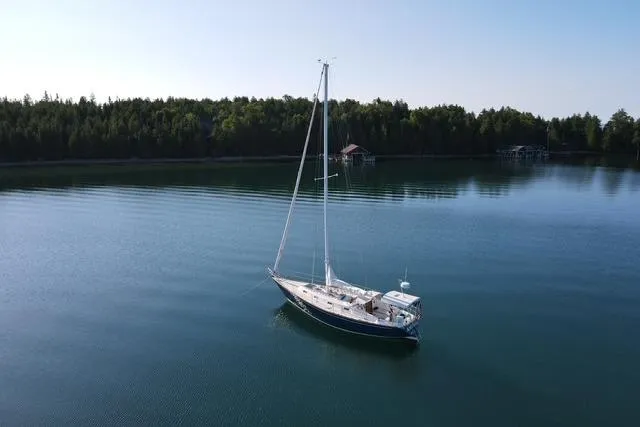 The Image of 1986 Tartan 37' sailboat on calm lake with forested shoreline. - 0