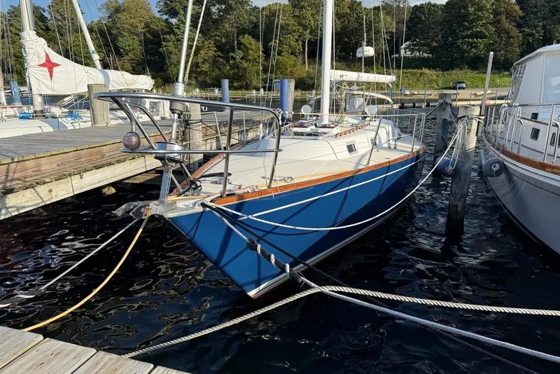 Slide: The Image of 1986 Tartan 37' sailboat docked at marina, featuring blue hull and wooden accents. - 2