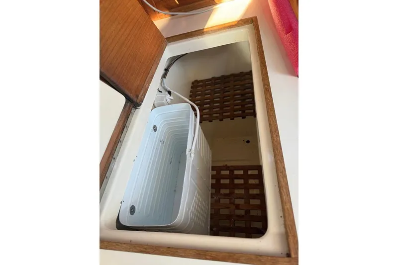 Slide: The Image of Open storage compartment on 1986 Tartan 37' sailboat with wooden trim and plastic container. - 23
