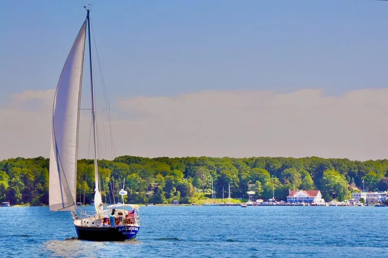 Slide: The Image of 1986 Tartan 37' sailboat cruising on a serene lake with lush green shoreline. - 33