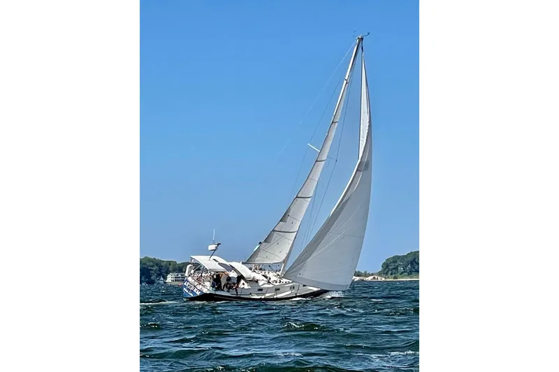 Slide: The Image of 1986 Tartan 37' sailboat navigating on open water under clear blue skies. - 9