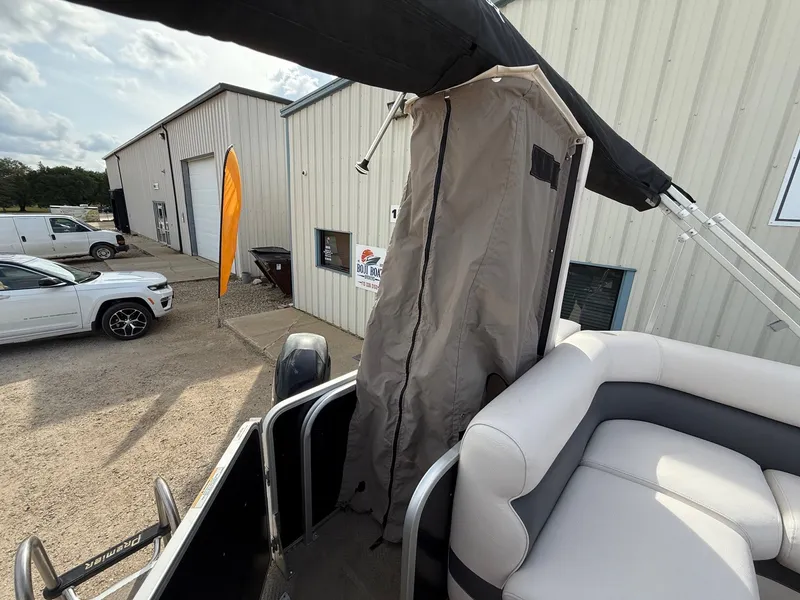 Slide: The Image of 2012 Premier 180 SunSation boat with canopy, parked near a building and vehicles. - 18