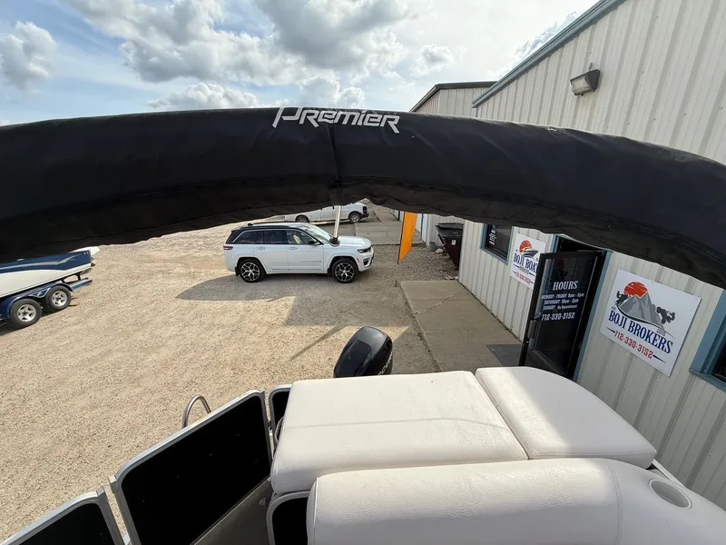 Slide: The Image of 2012 Premier 180 SunSation pontoon boat at dealership with white SUV and signage. - 19