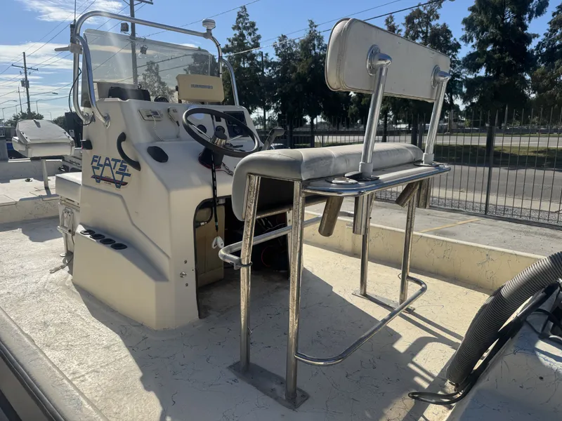 Slide: The Image of 2005 Flats Cat 21 boat interior with steering console and seating, parked outdoors. - 14