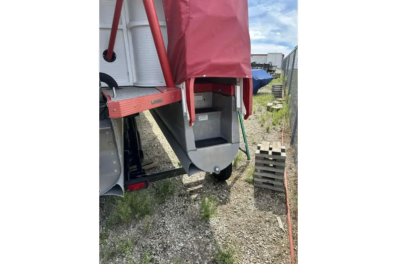 Slide: The Image of 2017 PlayCraft 2700 Extreme boat with red cover, parked on gravel. - 13