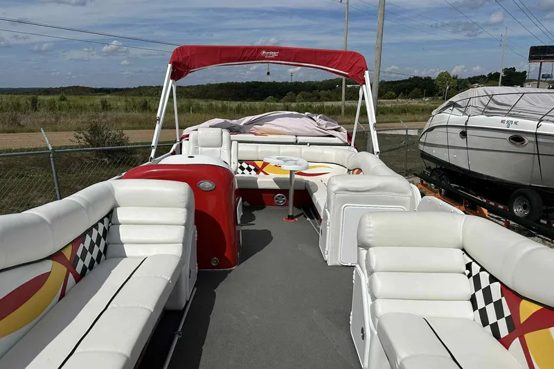 Slide: The Image of 2017 PlayCraft 2700 Extreme pontoon boat with red and white seating, parked outdoors. - 2