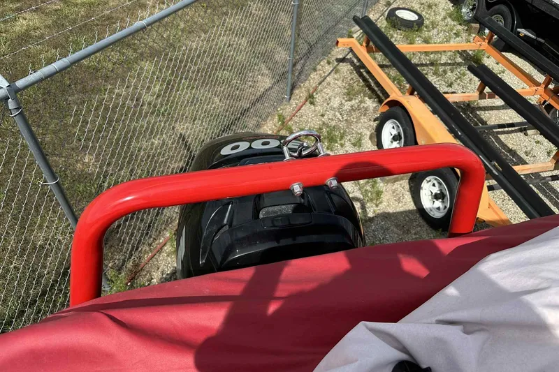 Slide: The Image of 2017 PlayCraft 2700 Extreme boat engine and trailer, viewed from above, near a chain-link fence. - 34