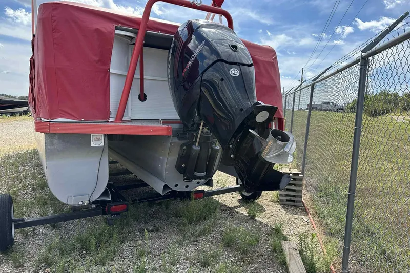Slide: The Image of 2017 PlayCraft 2700 Extreme boat with red cover and outboard motor, parked on gravel. - 36