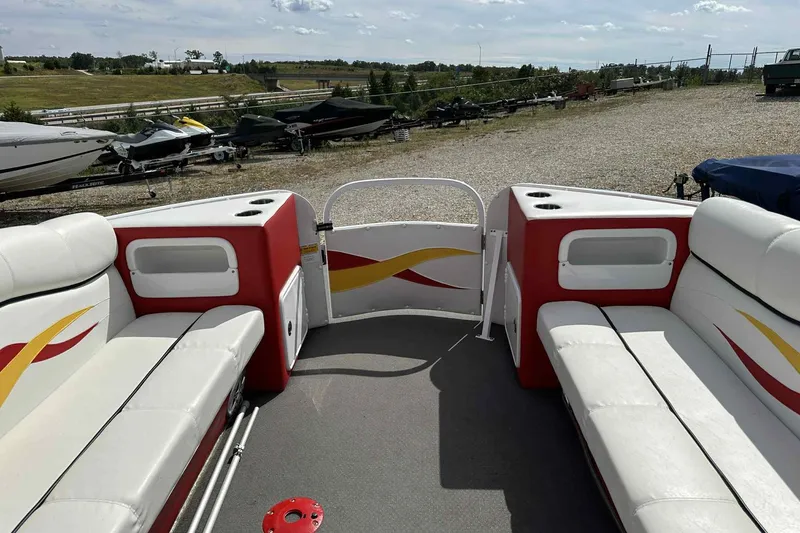 Slide: The Image of 2017 PlayCraft 2700 Extreme boat interior with white and red seating, parked outdoors. - 8