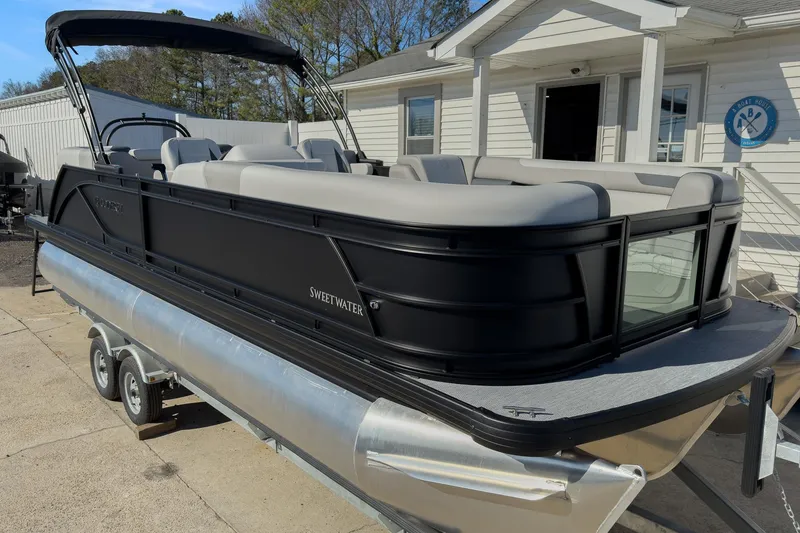 Slide: The Image of 2026 Godfrey Sweetwater 22' Split Bench Tritoon boat on trailer, parked outside a building. - 0