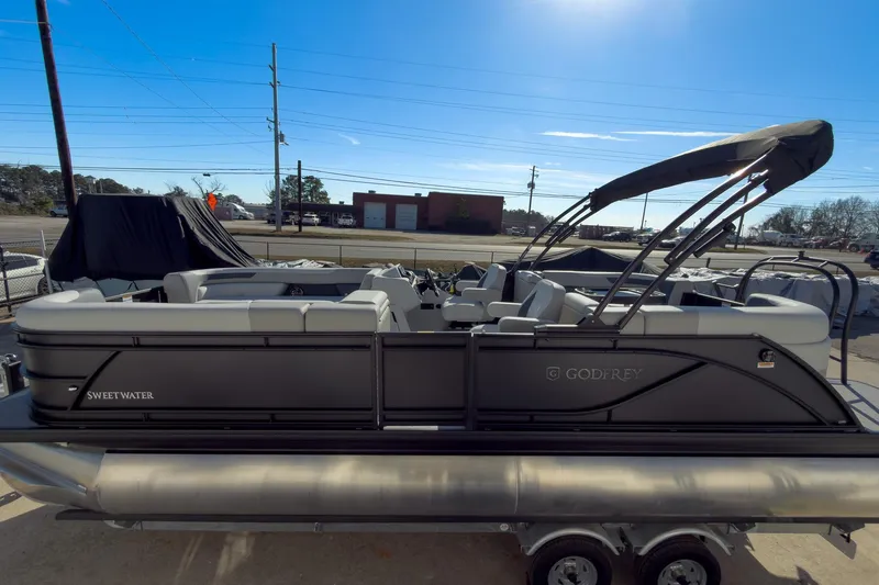 Slide: The Image of 2026 Godfrey Sweetwater 22' Split Bench Tritoon with canopy, parked outdoors. - 24