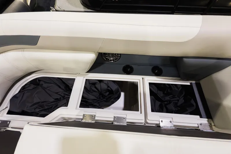 Slide: The Image of 2026 Godfrey Sweetwater 22' Tritoon storage compartments with black covers and cup holders. - 4