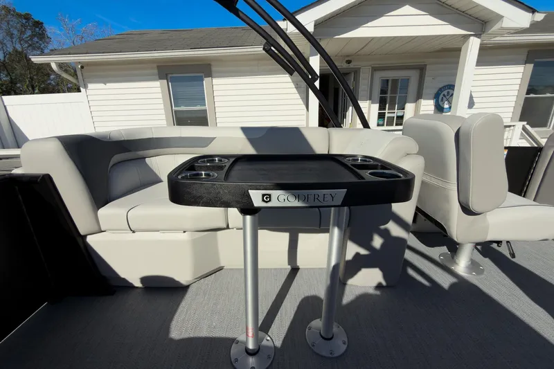 Slide: The Image of 2026 Godfrey Sweetwater 22' Tritoon interior with split bench seating and table. - 47