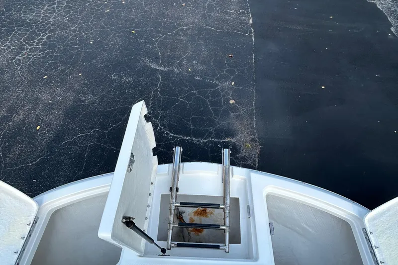 Slide: The Image of 2015 Bayliner 215 boat with open hatch and ladder on cracked pavement. - 12