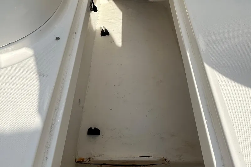 Slide: The Image of Storage compartment of a 2015 Bayliner 215 boat, featuring a clean, white interior. - 13