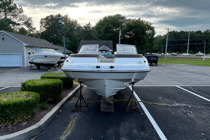 Slide: The Image of 2015 Bayliner 215 boat on display in a parking lot with greenery. - 3