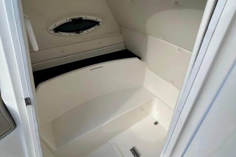 Slide: The Image of Interior cabin of 2015 Bayliner 215 boat, featuring sleek white design and compact space. - 9