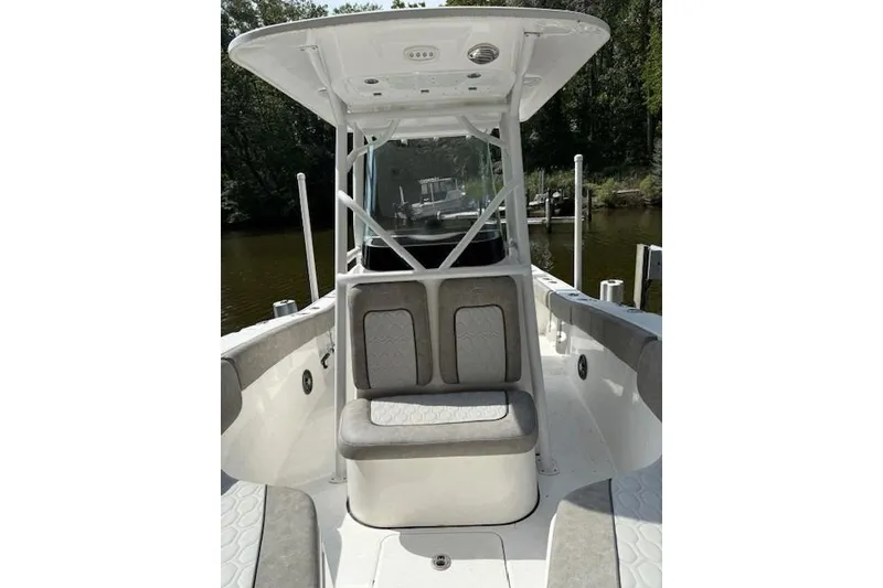 Slide: The Image of 2024 Sea Fox 228 Commander boat interior with seating and canopy, docked by a wooded shoreline. - 23