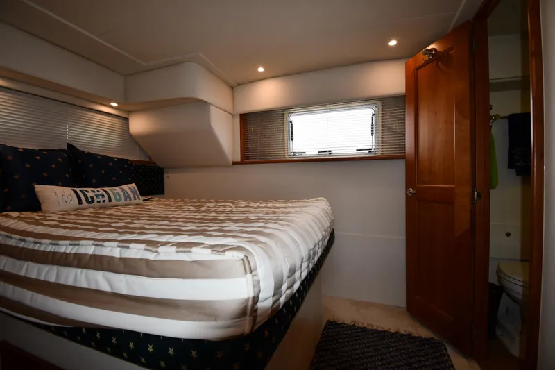 Slide: The Image of Cozy bedroom in 2000 Silverton 392 Motor Yacht with striped bedding and wooden door. - 48