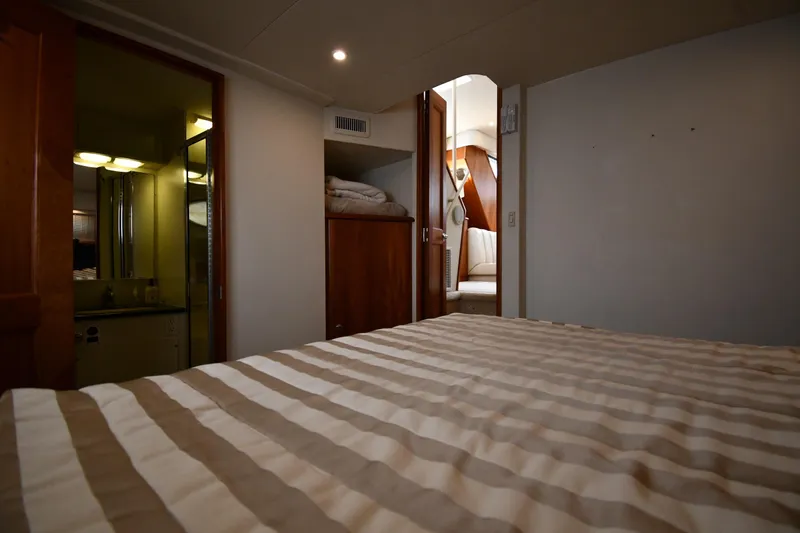 Slide: The Image of Interior of 2000 Silverton 392 Motor Yacht with striped bedding and bathroom view. - 50