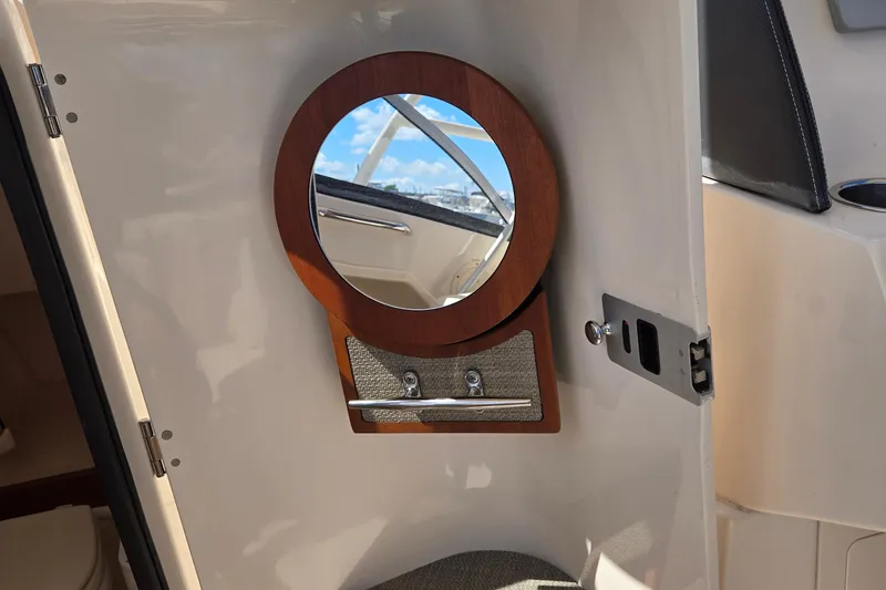 Slide: The Image of Interior of 2016 Grady-White Freedom 275 boat with round mirror and wooden frame. - 14