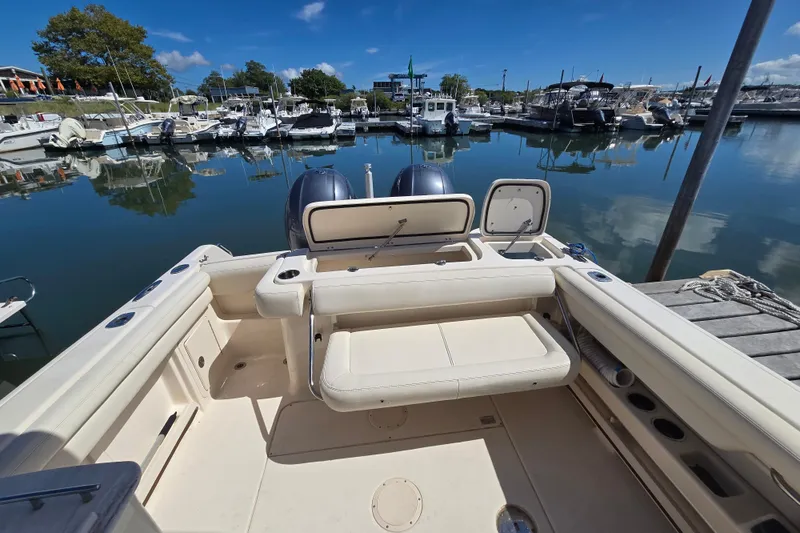 Slide: The Image of 2016 Grady-White Freedom 275 boat docked at a marina, showcasing spacious seating. - 16