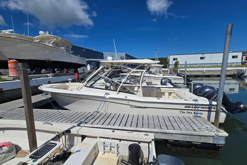 Slide: The Image of 2016 Grady-White Freedom 275 boat docked at marina under clear blue sky. - 4