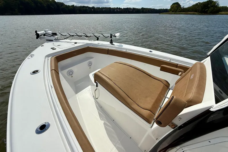 Slide: The Image of 2021 Sea Hunt Gamefish 27 Coffin Box boat interior with tan seating on a calm lake. - 10