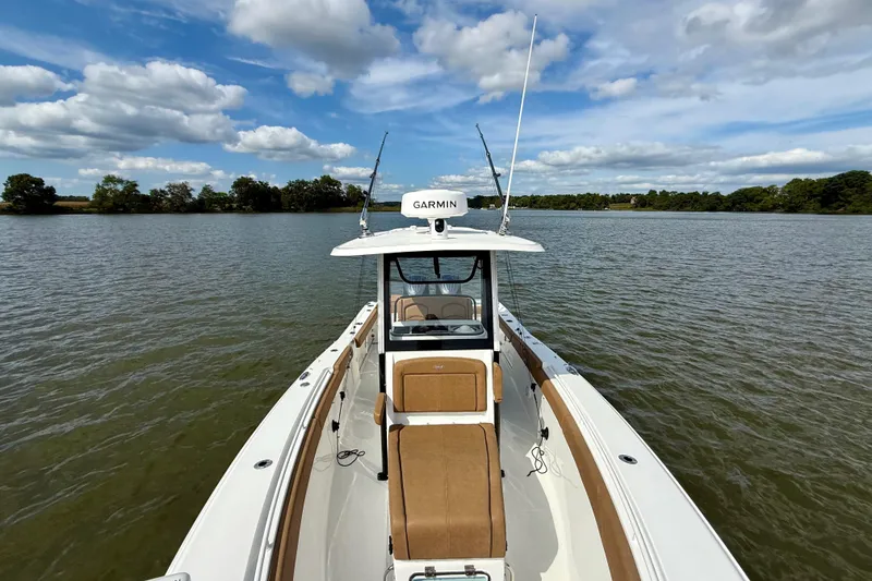 Slide: The Image of 2021 Sea Hunt Gamefish 27 Coffin Box boat on a serene lake under a blue sky. - 16