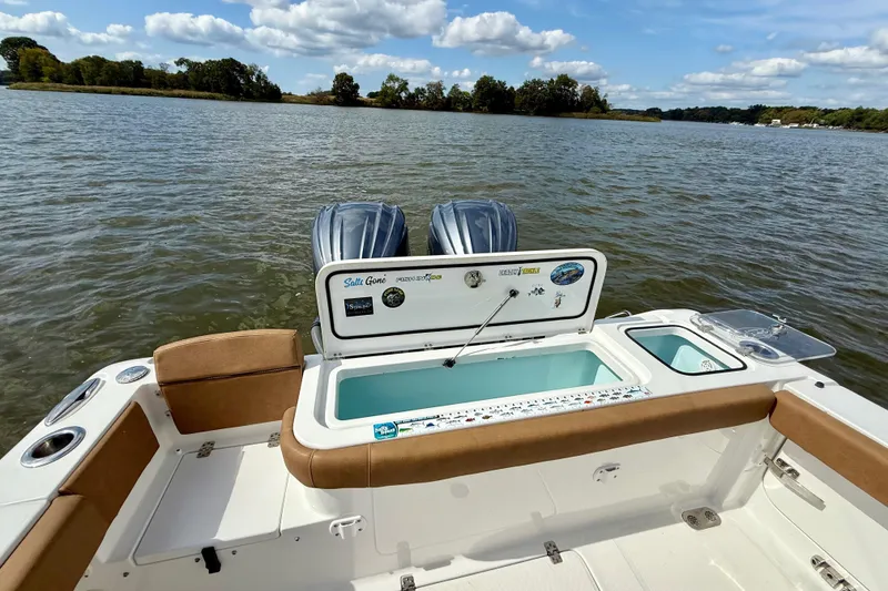 Slide: The Image of 2021 Sea Hunt Gamefish 27 Coffin Box boat on water, featuring dual engines and open storage. - 21
