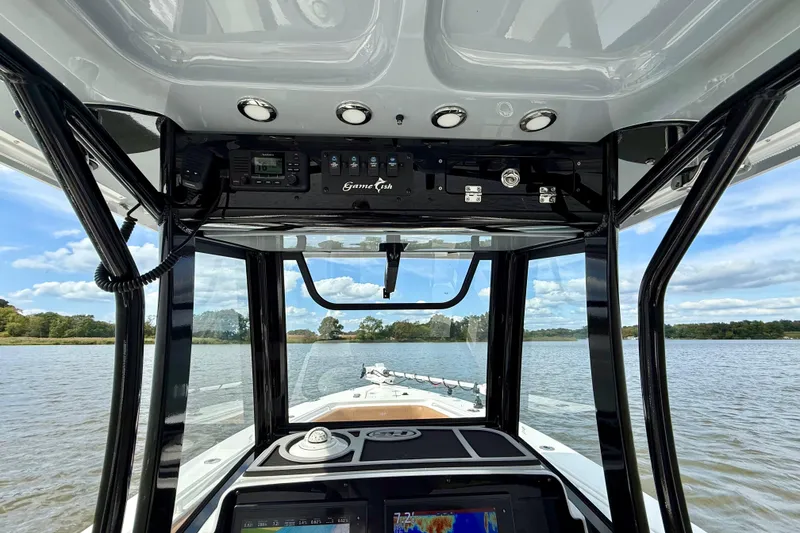 Slide: The Image of 2021 Sea Hunt Gamefish 27 Coffin Box boat interior with navigation equipment on a calm lake. - 26