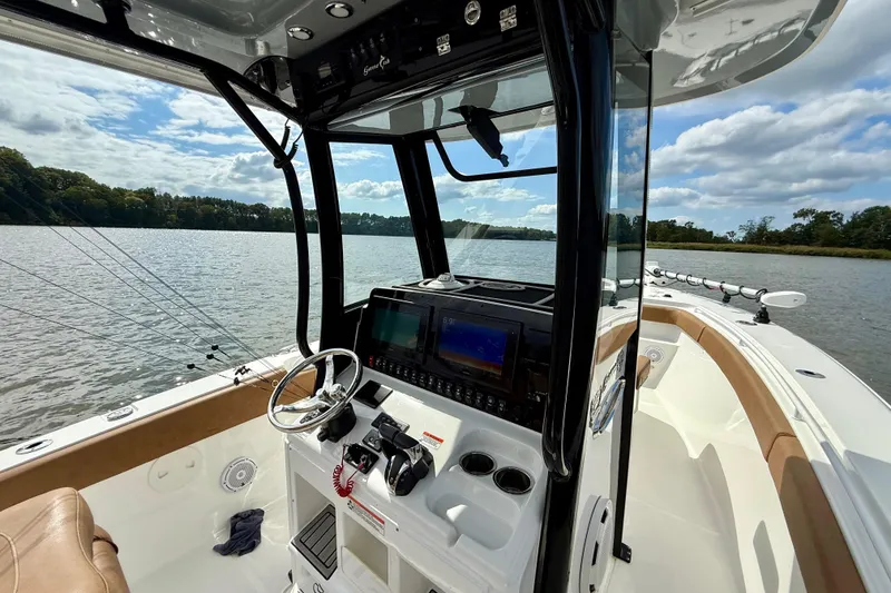 Slide: The Image of 2021 Sea Hunt Gamefish 27 Coffin Box boat interior with steering wheel and navigation screens. - 32
